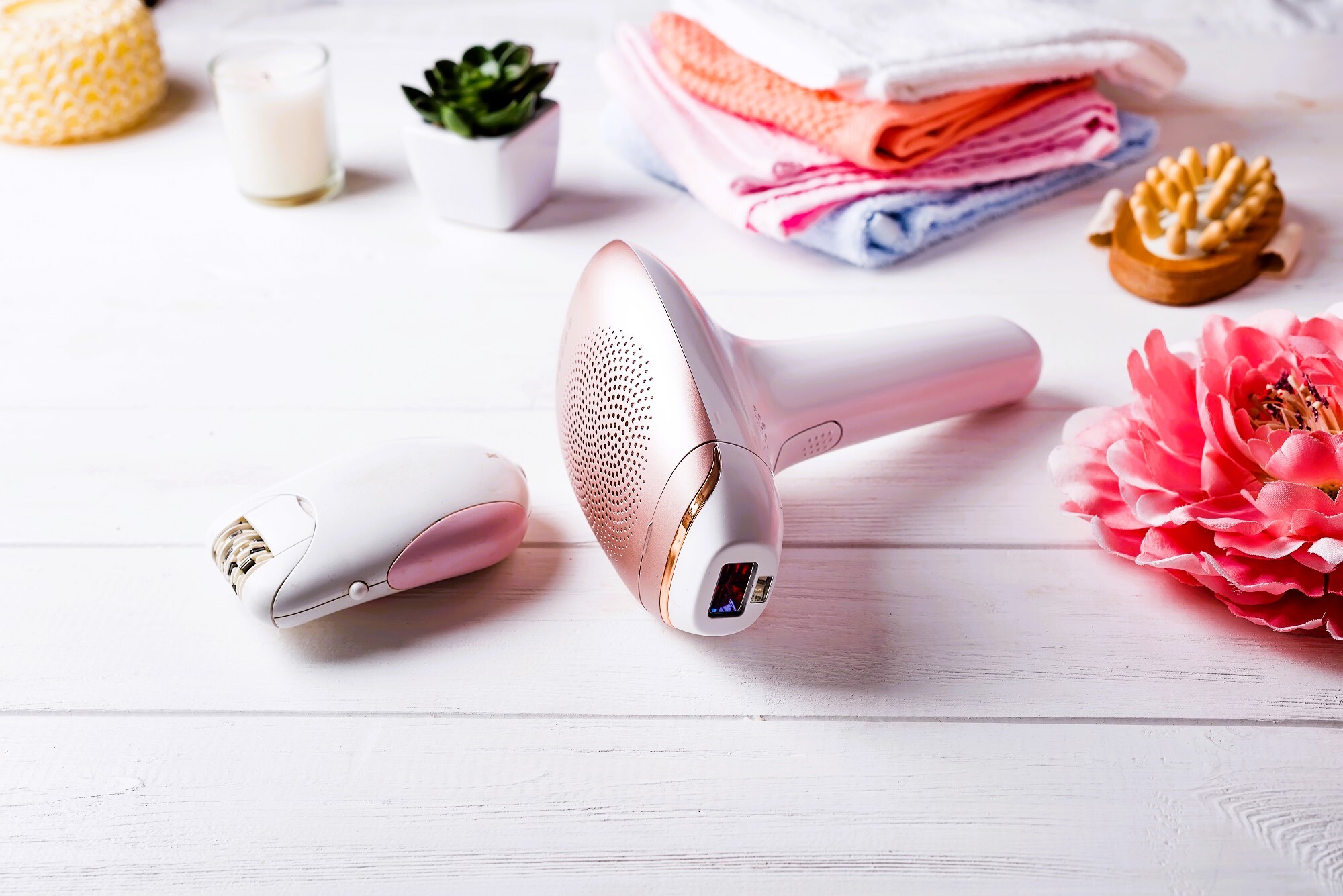 Modern laser epilator with bath accessories on white background.
