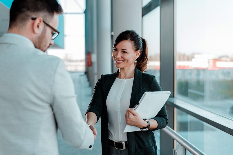 two-smiling-business-people-handshake-good-business-deal